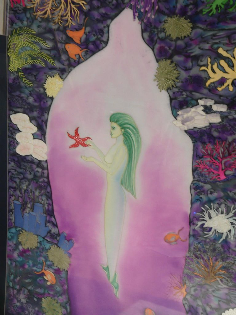 oeuvre sur soie représentant une sirène verte tenant une étoile de mer rouge à points blancs
